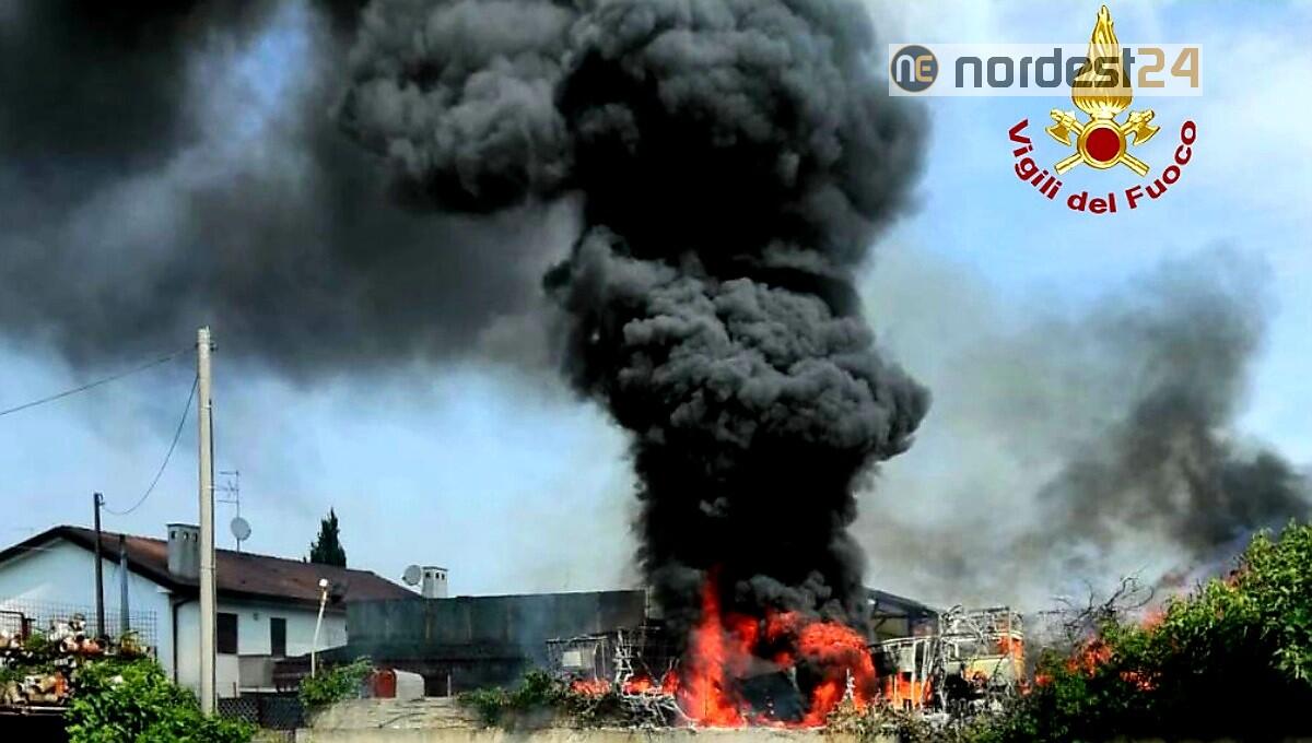 Fiamme e fumo alto nero dal cortile di un deposito edile - 