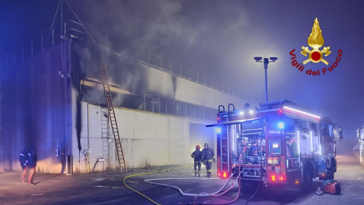 Fuoco in un capannone nella notte: alta colonna di fumo nel cielo - 